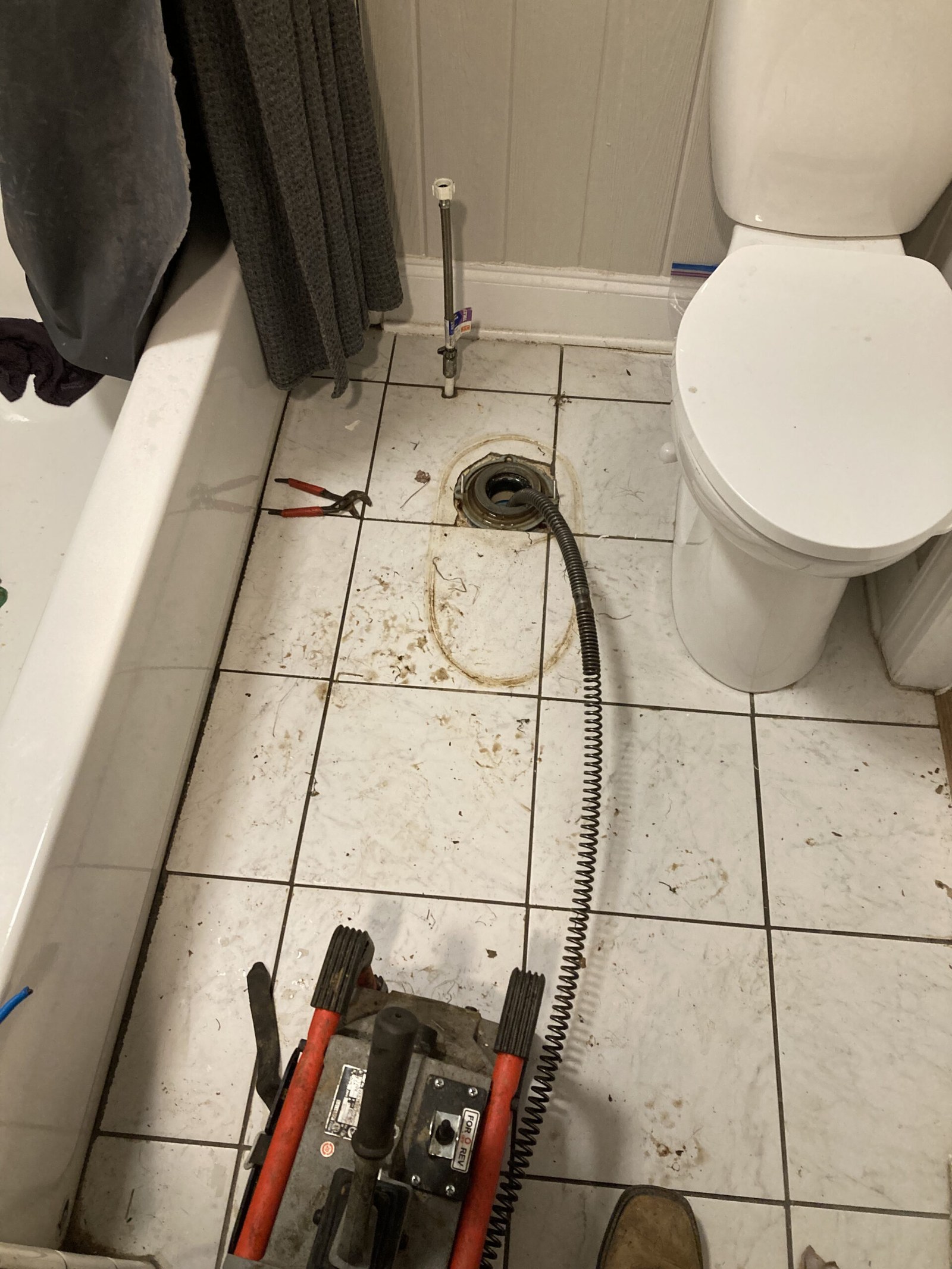 Drain cleaning machine working at a bathtub drain