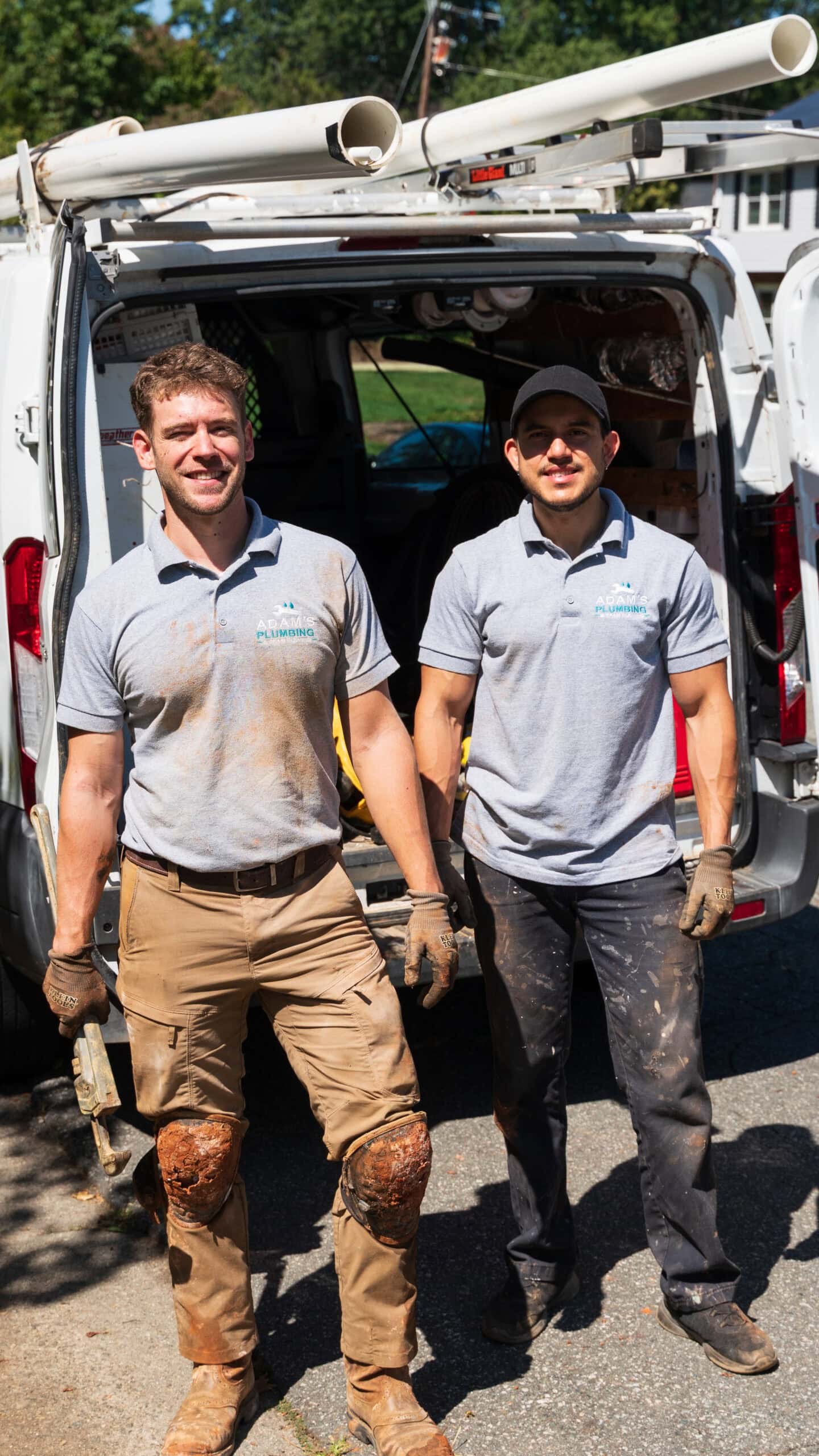 Adam Holder and a crew member standing in front of the work van, smiling